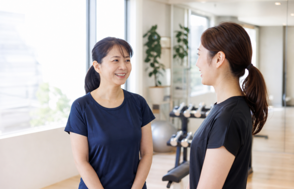 碧南市のジムPisteでトレーナーと笑顔で話す40代の看護師の女性